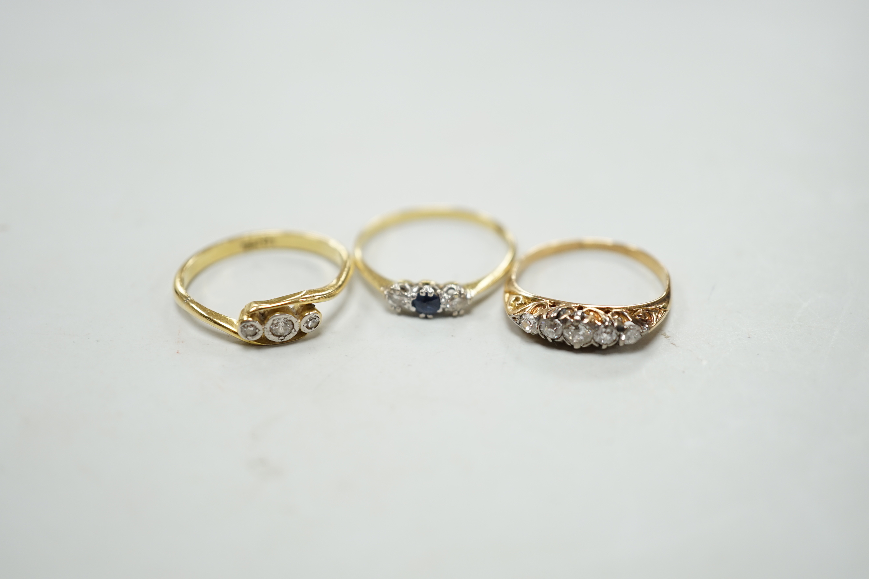 Two 18ct rings including illusion set three stone diamond and sapphire and diamond three stone and a yellow metal and graduated five stone diamond set half hoop ring, gross weight 5.8 grams.